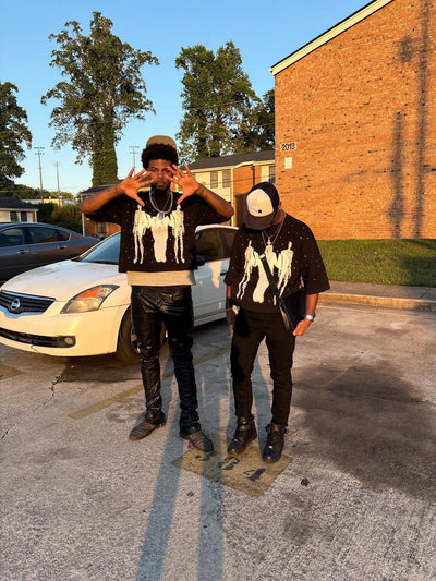Two individuals standing in a parking lot with a car and building in the background.